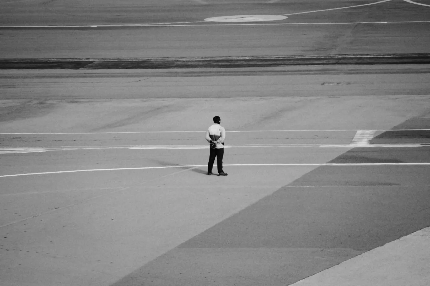 A ground crew member standing alone on an airport apron